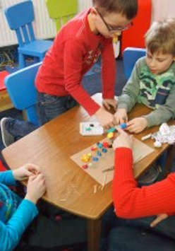 Dzieci przy stole podczas zajęć z plasteliną.