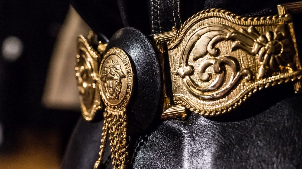 Złoty pas z wybijanymi wzorami, w jego centrum widnieje charakterystyczny dla Versace symbol głowy meduzy.