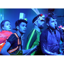 Na zdjęciu czworo młodych osób, stoją jeden za drugim, patrzą w tym samym kierunku, w rękach trzymają różne instrumenty muzyczne.