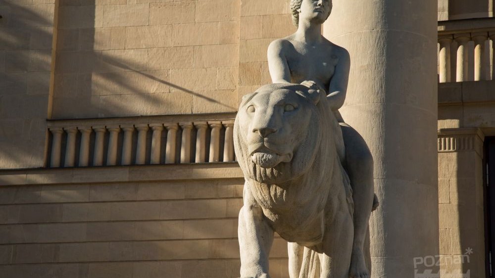 Oświetlona słońcem marmurowa rzeźba z lwem na schodach Teatru Wielkiego.