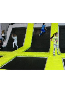 Dzieci na trampolinach oddzielonych żółtymi materacami.