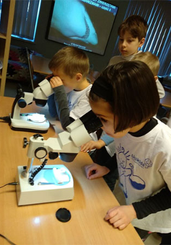 Foto: Dwoje dzieci oglada preparaty przez mikroskopy.