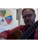 Męszczyzna gra na gitarze. Po lewej logo Przystani Artystycznej.