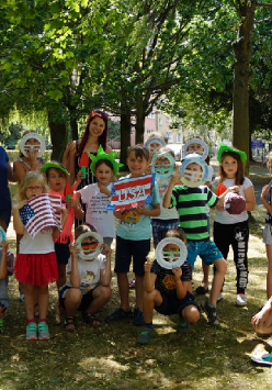 Dzieci z opiekunką podczas półkolonii, trzymające gadżety.