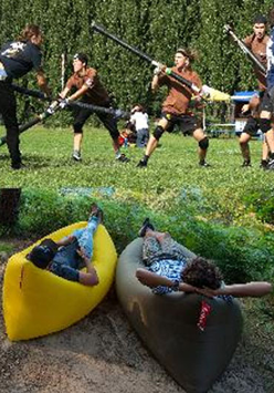 grupa chłopców walczy na trawie, 2 odpoczywa w canoe.
