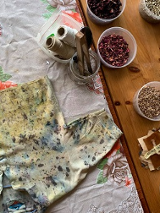 Na stol materiał a na nim koszulka do farbowania. Obok w pojemnikach produktu do robienia naturalnych barwników.