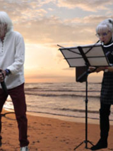 Danuta i Dariusz Stoccy koncertują na plaży. W tle morze.