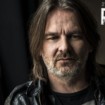 Fotografia przedstawia portret artysty patrzącego prosto w obiektyw.