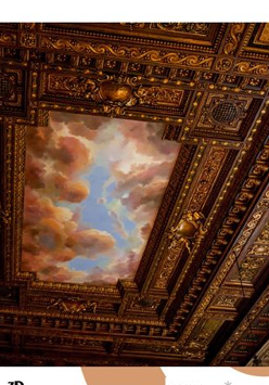 Widok zdobionego, rzeźbionego, drewnianego sufitu z malunkiem nieba i chmurami.