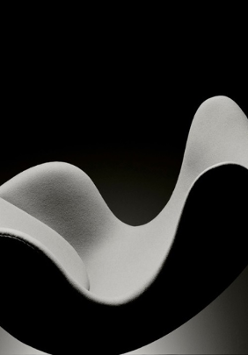 Na czarno białej fotografii Piotra Topperzera widzimy fotel w kształcie przypominającym jajko. Fotel jest bez nóg i sprawia wrażenie bujanego fotela lub skulonego nagiego ciała ludzkiego.