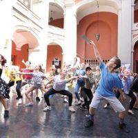 Wychowankowie szkoły baletowej tańczą na dziedzińcu szkoły.