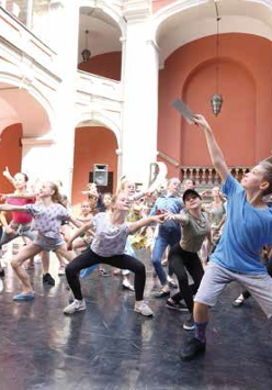 Wychowankowie szkoły baletowej tańczą na dziedzińcu szkoły.