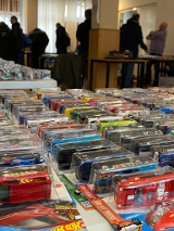 Na stolikach rozłożone samochodziki zabakowe marki Hotwheels. Między stolikami chodzą kupujący.