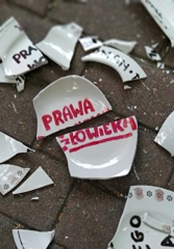 Porozbijana ceramika z napisem "prawa człowieka" na kostce brukowej.
