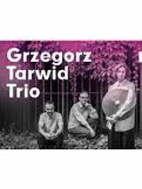 Grafika przedstawia czarno-białe zdjęcie trzech mężczyzn. Jeden z mężczyzn trzyma talerz od perkusji. Na górze pada na nich fioletowe światło.