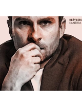 na bladoróżowym tle fragment postaci mężczyzny w brązowej marynarce. Mężczyzna trzyma dłoń przy ustach patrząc wprost w obiektyw, na ramieniu marynarka ma białą plamę.