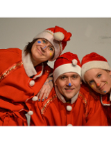 na zdjęciu trzy osoby ubrane w czerwone stroje Mikołaja, uśmiechnięte patrzą w obiektyw. Na nosach, brodzie i policzkach twarzach mają wymalowane kolorowe kropki.