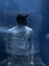 Zdjęcie stojącego mężczyzny, który patrzy w bok. Niebieskie, rozmyte tło.