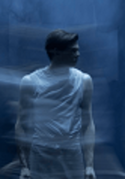 Zdjęcie stojącego mężczyzny, który patrzy w bok. Niebieskie, rozmyte tło.