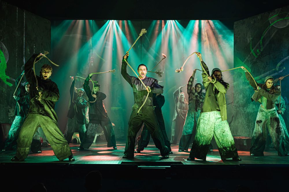 Grupa ludzi wymachuje nad głowami grubymi sznurami trzymanymi w rękach.