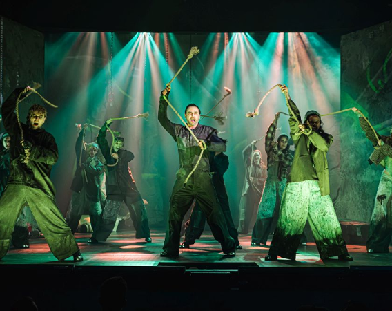 Grupa ludzi wymachuje nad głowami grubymi sznurami trzymanymi w rękach.