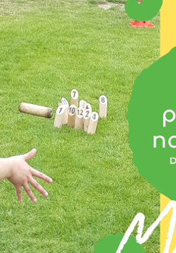 Plakat o grach plenerowych, na którym dziecko kuca na trawie a przed nim rozstawione sa drewniane klocki.