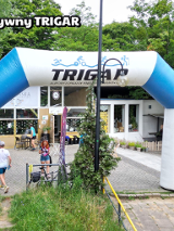 Meta biegu charytatywnego. W tle budynek kawiarni w środku parku. Po prawej duża szachownica i dużymi pionkami.