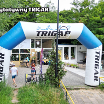 Meta biegu charytatywnego. W tle budynek kawiarni w środku parku. Po prawej duża szachownica i dużymi pionkami.