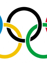 Pięć kół olimpijskich nachodzących na siebie. Trzy koła w górnym rzędzie (niebieskie, czarne i czerwone), dwa koła w dolnym rzędzie (żółte i zielone).