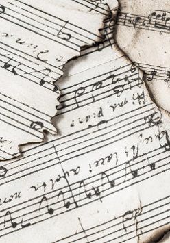 Rozrzucone fragmenty utworów zapisane na pięciolini.