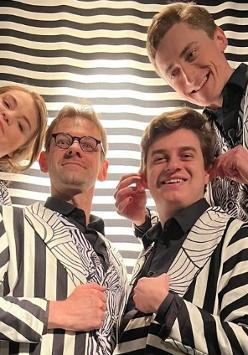 Zdjęcie aktorów - kobieta i trzech mężczyzn we frakach w biało-czarne paski.