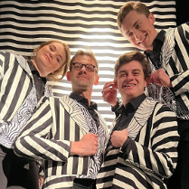 Zdjęcie aktorów - kobieta i trzech mężczyzn we frakach w biało-czarne paski.