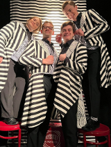 Zdjęcie aktorów - kobieta i trzech mężczyzn we frakach w biało-czarne paski.