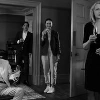 Ludzie stojący w salonie i pijący szampana. Zdjęcie czarno-białe.