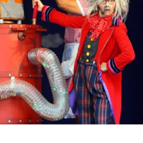 zdjęcie przedstawia postać w kolorowym stroju stojącą przy machinie przypominjącej rakietę