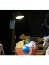 na zdjęciu dwie lalki teatralne: starszy pan stoi po lewej stronie, starsza pani po prawej, pomiędzy nimi wózek dziecięcy. Nad lalkami widoczne ręce aktorów.