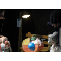 na zdjęciu dwie lalki teatralne: starszy pan stoi po lewej stronie, starsza pani po prawej, pomiędzy nimi wózek dziecięcy. Nad lalkami widoczne ręce aktorów.