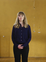 Kobieta stojąca na sali gimnastycznej. W tle widoczna bramka oraz kosz.