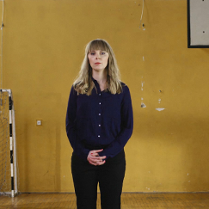 Kobieta stojąca na sali gimnastycznej. W tle widoczna bramka oraz kosz.