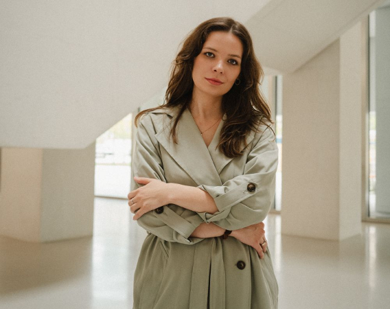 Kobieta w beżowym trenczu i rozpuszczonych włosach.