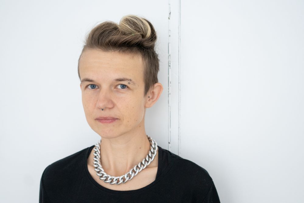 Kobieta w blond włosach, z kolczykami w nosie oraz brwi.