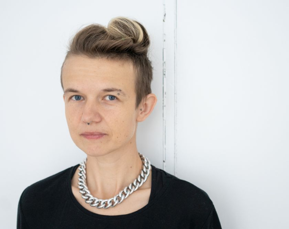 Kobieta w blond włosach, z kolczykami w nosie oraz brwi.