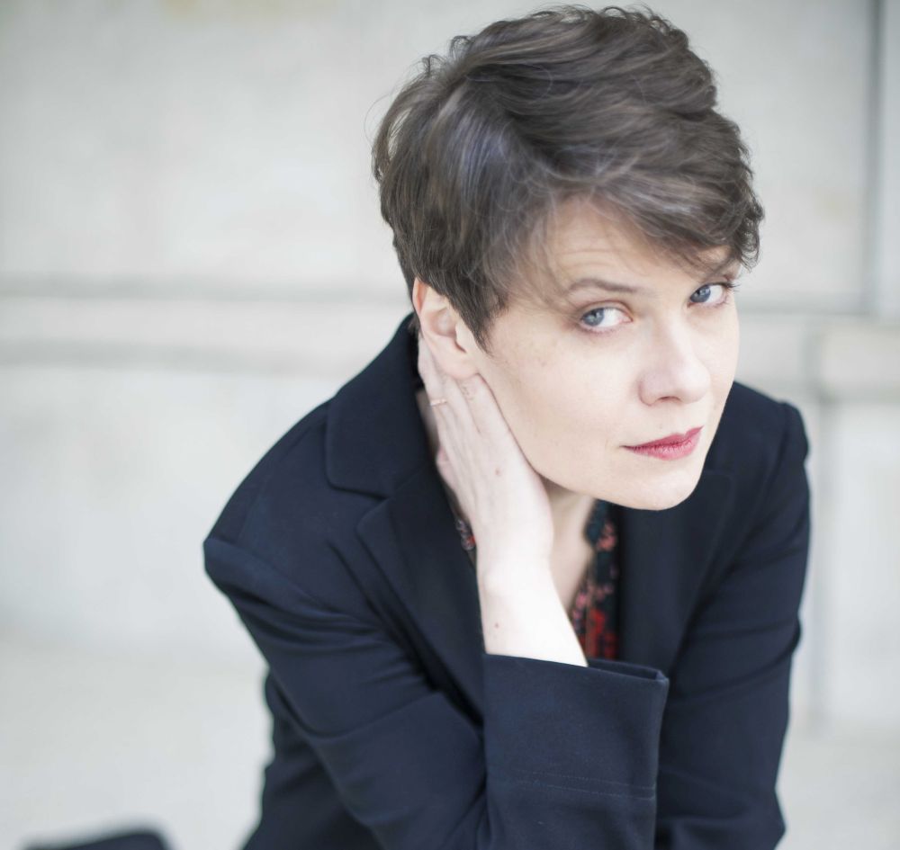 Kobieta w krótkiej fryzurze podpiera głowę ręką.