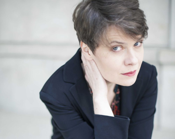 Kobieta w krótkiej fryzurze podpiera głowę ręką.