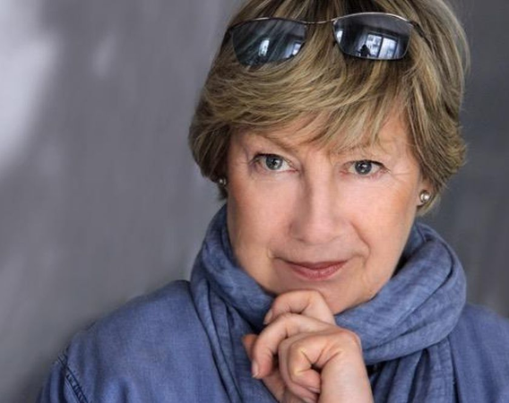 Kobieta w średnim wieku podpierająca ręką brodę.