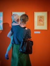 Kobieta z małym dzieckiem na rękach oglądająca obrazy