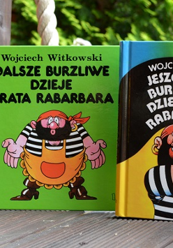 Trzy ksiązki stojące obok siebie z kolorowymi okładkami z piratem. W tle zielone drzewa.