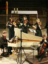 Koncert. Muzycy graja na fortepianie i istrumentach smyczkowych.