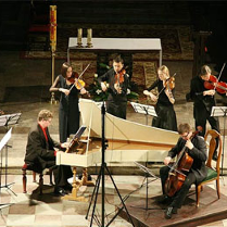 Koncert. Muzycy graja na fortepianie i istrumentach smyczkowych.