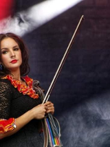 Kobieta z instrumentem stojąca na scenie.